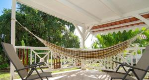 a hammock on a porch with two chairs at Appartement spacieux au Vauclin avec piscine privée in Le Vauclin