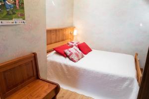 a small bedroom with a white bed with red pillows at Appartement chaleureux à Gresse-en-Vercors 43 m² vue montagne in Gresse-en-Vercors +6 photos