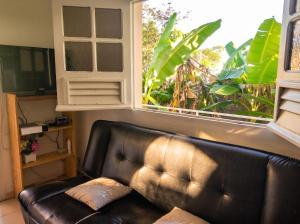 a leather couch in a living room with a large window at Appartement charmant au Lamentin avec terrasse et jardin, 46 m² in Le Lamentin