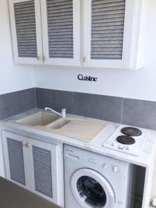 a kitchen with a sink and a washing machine at Studio romantique à Saint-François - 25 m² avec piscine in Saint-François