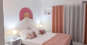 a bedroom with a white bed with a red fan on the wall at Studio romantique à Saint-François - 25 m² avec piscine in Saint-François