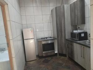 a small kitchen with a refrigerator and a microwave at Unitas Park B&B in Vereeniging