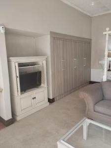 a living room with a tv and a couch at Unitas Park B&B in Vereeniging