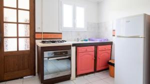 a kitchen with red cabinets and a white refrigerator at Maison charmante Le Moule + piscine in Le Moule