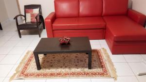 a living room with a red couch and a coffee table at Maison charmante Le Moule + piscine in Le Moule