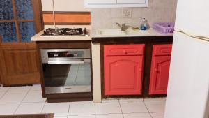 a kitchen with red cabinets and a stove and a sink at Maison charmante Le Moule + piscine in Le Moule +4 photos
