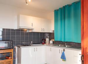 a kitchen with white cabinets and a green curtain at Appartement moderne avec vue mer à Bouillante, 50 m² in Bouillante