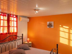 a bedroom with a bed with an orange wall at Appartement moderne avec vue mer à Bouillante, 50 m² in Bouillante