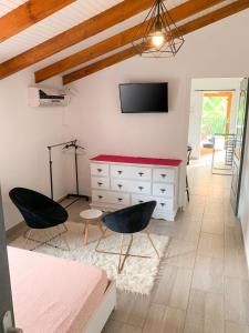 a bedroom with a dresser with a tv and two chairs at Studio cosy à Capesterre-Belle-Eau avec terrasse in Capesterre-Belle-Eau