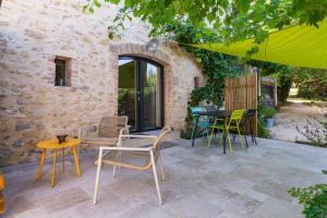a patio with chairs and a table in front of a building at Gîte La Peyrolle in Aouste-sur-Sye