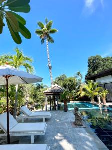 a resort with a palm tree and a swimming pool at Panya Samui in Choeng Mon Beach