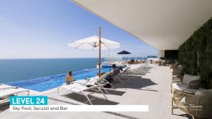 a pool with chairs and an umbrella and the ocean at Encantame Velero Ground Floor, BeachFront in Playa Encanto +43 photos