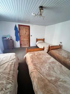 a room with three beds and a door at Bjeshket e Thethit Hostel in Theth