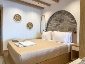 a bedroom with a bed with a stone wall at Marizon Suites - Adults Only in Vrachonisída touArchangélou