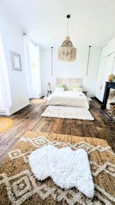 a white bedroom with a bed and a chandelier at L'héritage in Champdeniers