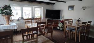 a dining room with tables and chairs and a flat screen tv at Pension Pencik in Kurort Altenberg