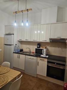 a kitchen with white cabinets and a sink and a microwave at Casa Saudade Beach House in Zambujeira do Mar +2 photos