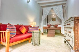 a living room with a red couch and a bed at Dar Latigeo in Essaouira