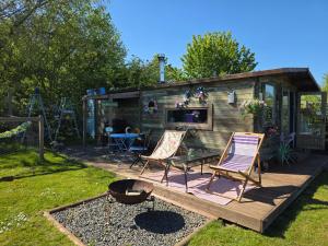 a backyard with two chairs and a table and a house at Lakeview Petting Pod in Chelmsford