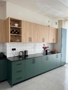 a kitchen with green cabinets and black counter tops at Mandarini in Chakvi