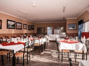 a dining room with tables and chairs and a kitchen at Rosahoff Guesthouse in Windhoek