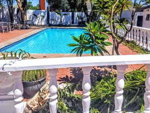 a swimming pool with a white fence and plants at Rosahoff Guesthouse in Windhoek