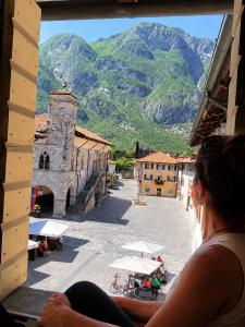 a woman looking out of a window at a town with mountains at Venzone dalla Finestra in Venzone