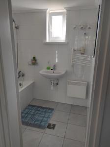 a white bathroom with a sink and a shower at Apartman Garami Porta in Mezőkövesd