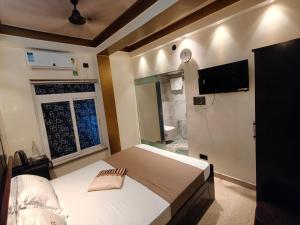 a bedroom with a bed and a tv on the wall at Hotel Joy Guru Inn in Durgāpur