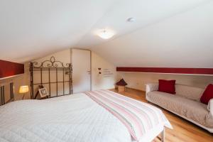 a bedroom with a white bed and a couch at Une parenthèse en Ardenne in Nollevaux
