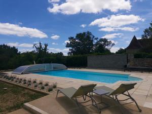 a swimming pool with two lawn chairs and a patio at B&B Manoir Calmeer in Thenon