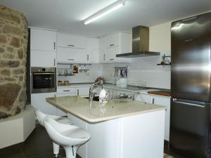 a white kitchen with a sink and a refrigerator at Casa da Poza in A Estrada