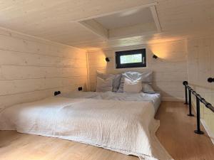 a bedroom with a white bed in a wooden wall at Großzügiges Tiny House in Sumte
