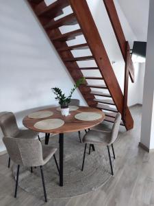 a table and chairs in a room with a staircase at Campana Apartment - Szigetvár in Szigetvár