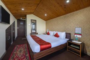 a bedroom with a large bed and a television at The Prakriti Heights l Lift l Comfortable And Spacious Rooms l Free Wifi, Free Parking l Enjoy Fresh Mountain Air l Managed By Exotic stays in Shimla