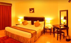 1 dormitorio con cama, escritorio y espejo en Nelover Hotel Hafar, en Hafr Al Batin