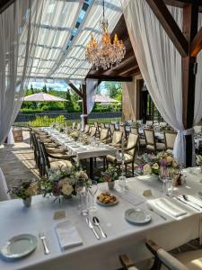 a dining room with white tables and chairs and a chandelier at Park Hotel Popovicky in Popovičky