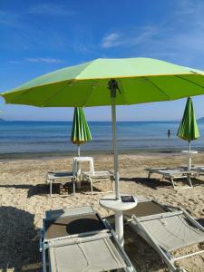 two chairs and a green umbrella on a beach at Matteo Garden & Restaurant in Vlorë