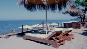 a beach with two beds and an umbrella and the ocean at Eden Hotel in Rrogozhinë