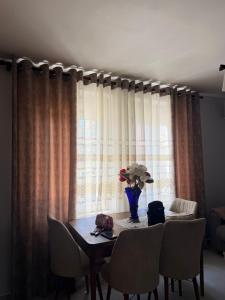 a dining room table with chairs and a vase of flowers at Bella Vista Apartment in Lezhë