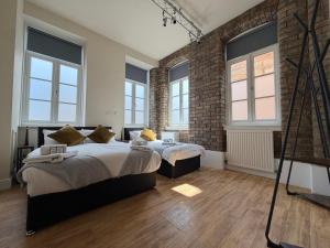 two beds in a room with a brick wall at The Holyrood Mega-Quarters in Edinburgh