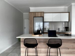 a kitchen with two bar chairs and a counter at Summer Set West in Somerset West
