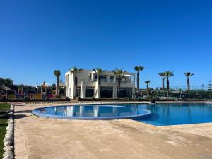 a large swimming pool in front of a house at Villa Savannah Beach in Sidi Rahal