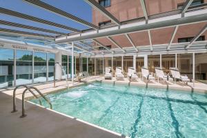 a large swimming pool with chairs in a building at Salles Ciutat del Prat Barcelona Airport in El Prat de Llobregat