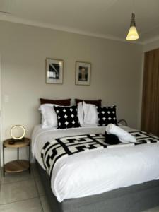 a bedroom with a large bed with black and white pillows at Summer Set West in Somerset West +19 photos