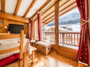 a bedroom with a balcony with a bed and a television at Chaleureux appartement au pied des pistes avec parking et animaux admis - FR-1-505-65 in Notre-Dame-de-Bellecombe