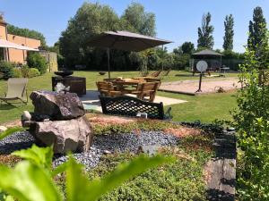 a park with a bench and an umbrella and a table at Les Loges Du Ried in Marckolsheim