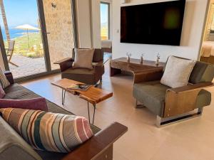 a living room with couches and a flat screen tv at Villa Thea with Pool & panoramic Sea View in Kotrónion