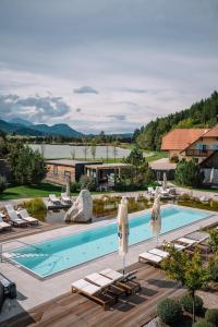 a swimming pool with lounge chairs and umbrellas at Lakeside Petzen Glamping in Unterlibitsch