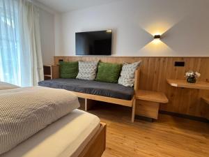 a bedroom with a couch with a tv on the wall at Alpenrösle Ferienwohnungen - Berge - Ruhe - Traumaussicht 1-, 2- und 3-Raum-Wohnungen, Panoramasauna in Balderschwang